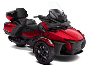 A luxurious red and black Can-Am Spyder RT Limited Deep Marsala Edition three-wheeled motorcycle. The bike features a full touring setup with a comfortable passenger seat, a large windscreen, and ample storage compartments. The design is aerodynamic with ergonomic handlebars and black alloy wheels, offering both style and comfort for long-distance rides.