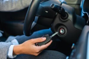 Close-up of a hand putting out a car key from the ignition of a vehicle's steering column.