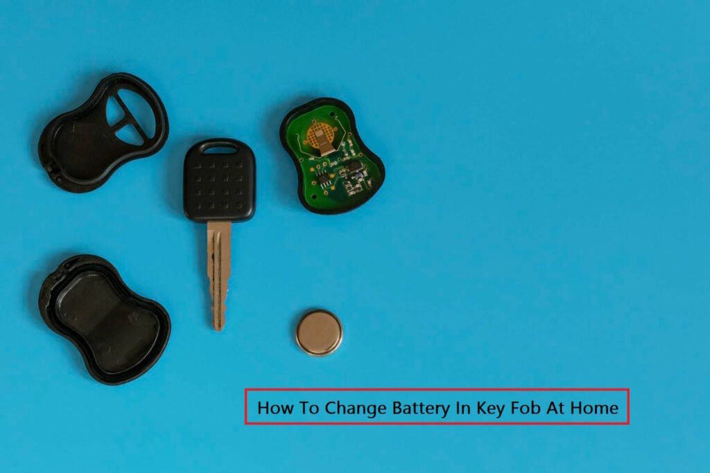 Disassembled car key fob placed on a blue surface showing the key blade, internal circuit board, outer casing, and a button cell battery. The text "How To Change Battery In Key Fob At Home" is displayed in a red box at the bottom.