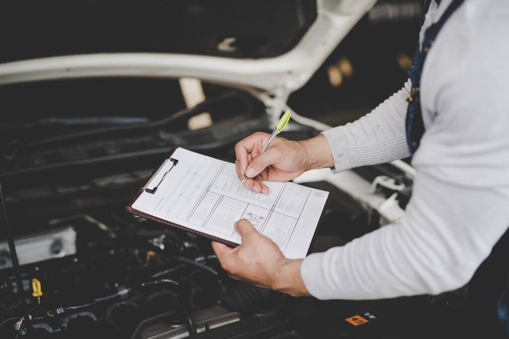 A mechanic holding a checklist and inspecting a car engine during a vehicle inspection.