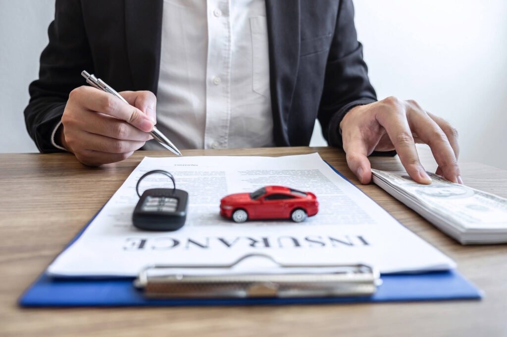 Insurance agent reviewing auto insurance documents with toy car and key fob on desk