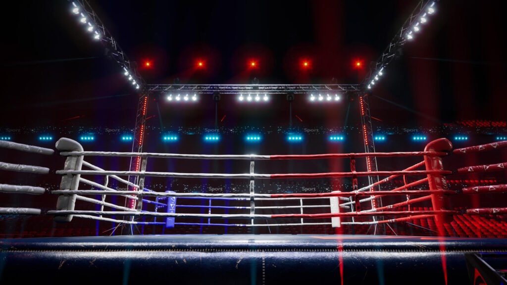 Professional wrestling ring with dramatic red and blue lighting in a large arena, featuring multiple rope levels and professional broadcast lighting setup