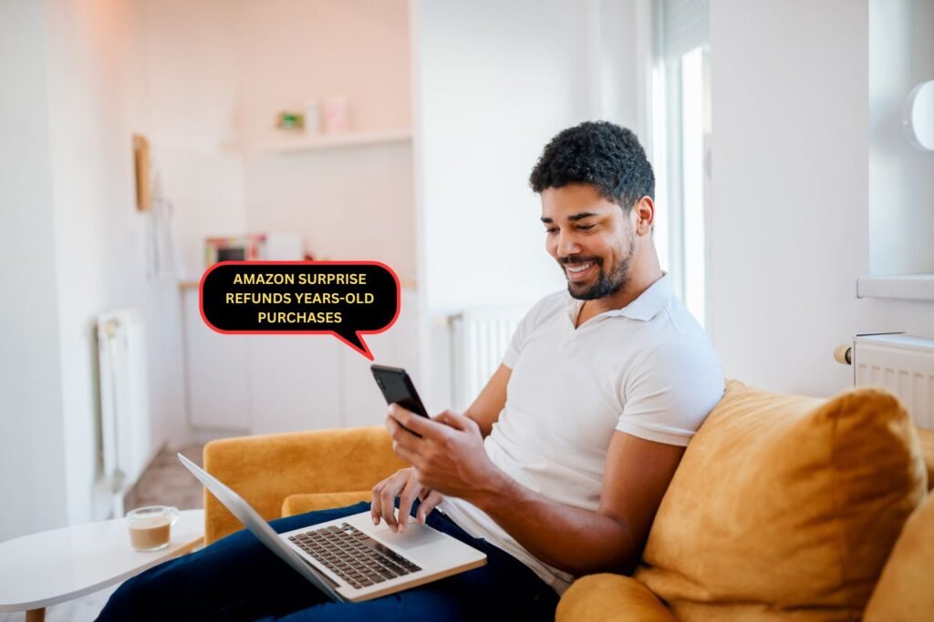 Happy man sitting on yellow couch with laptop and smartphone checking Amazon surprise refunds for years-old purchases