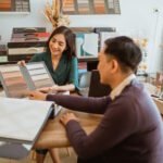 Professional interior designer showing material samples to client during home decoration consultation in modern office space