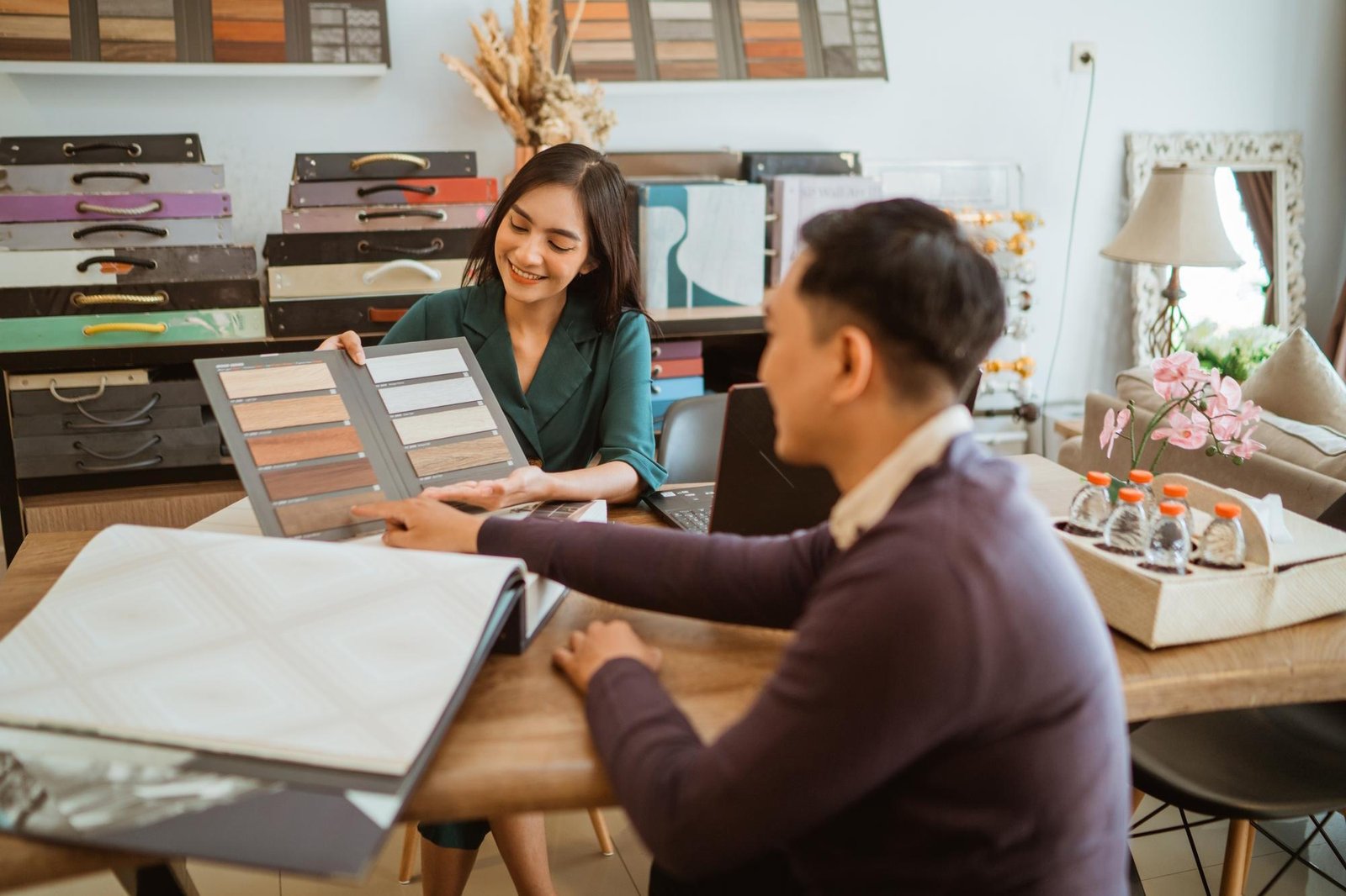 Professional interior designer showing material samples to client during home decoration consultation in modern office space