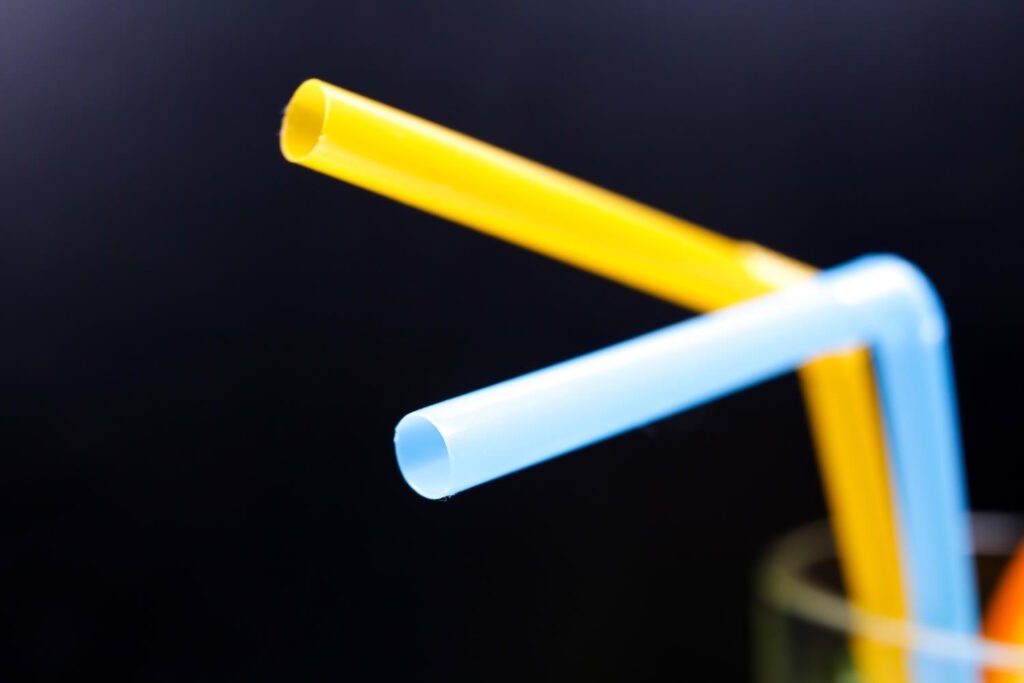 Close-up of bent yellow and light blue thermoplastic tubes or rods against a dark background, demonstrating the flexibility and moldability of thermoplastic materials.