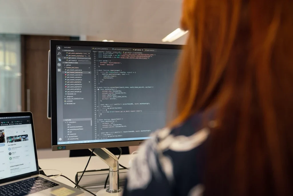Developer working on business intelligence dashboard code with data visualization tools on multiple screens